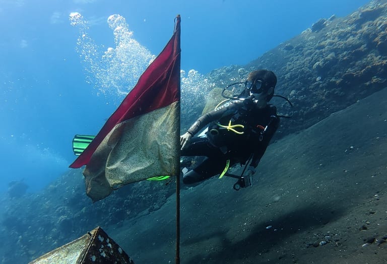 Penyelam melewati bendera Indonesia bawah air di Liberty Wreck Tulamben